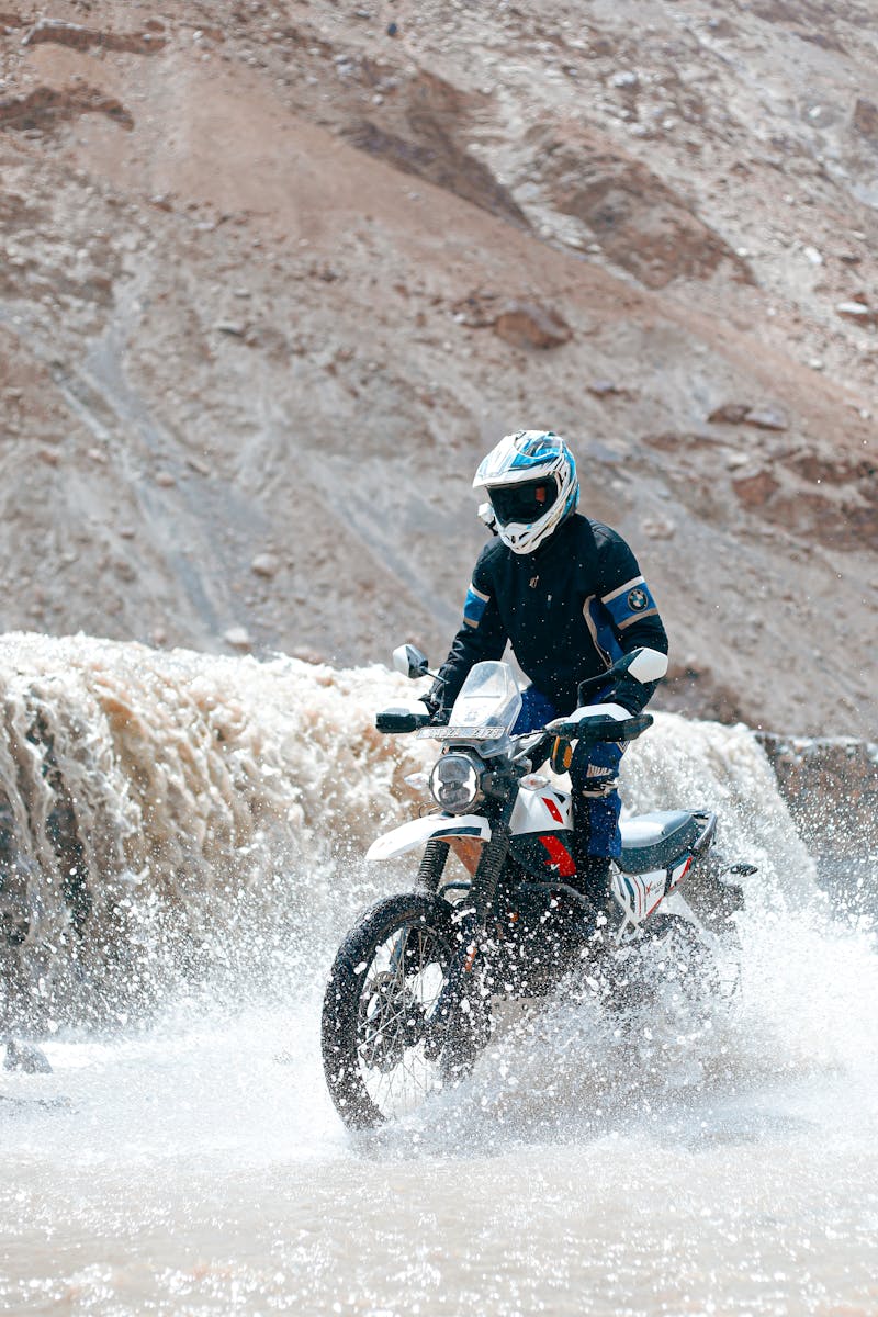 A person riding a motorcycle through a waterfall